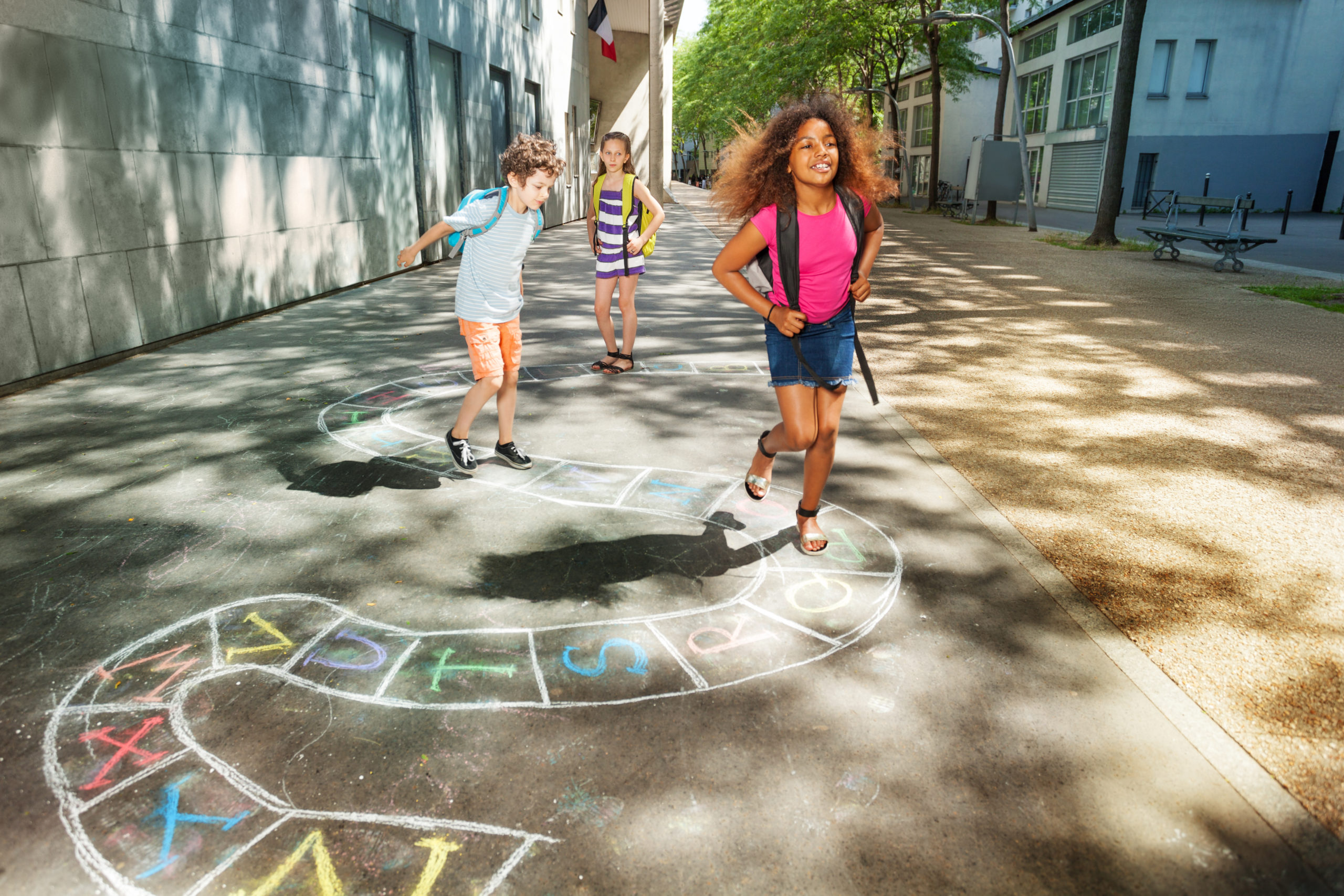 Group of kids jumping and paying hopscotch game outside near the school together